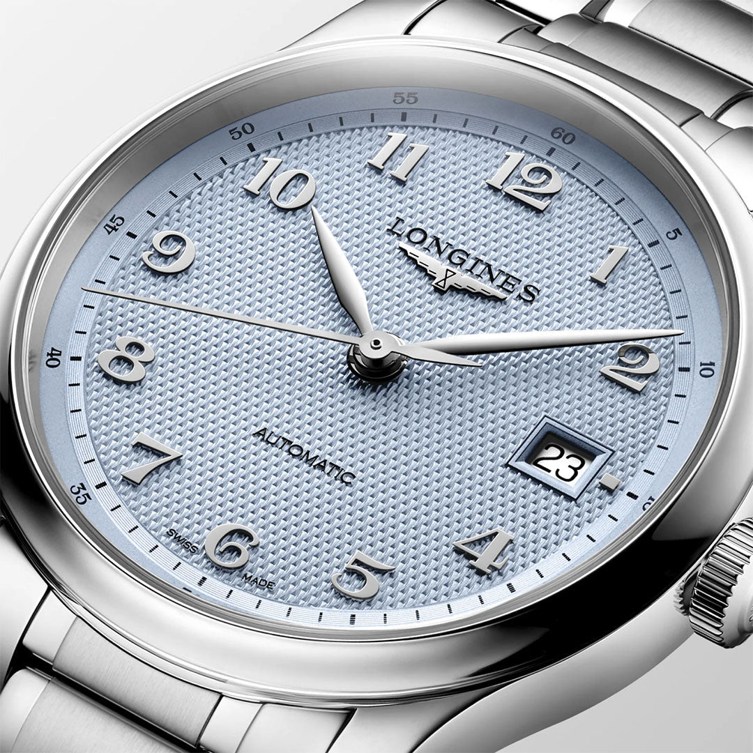 Close-up of the Longines Master Collection Automatic 39mm Watch by Longines, featuring a textured light blue dial with silver hour markers, a date display at 3 o’clock, and a metal bracelet. The luxury wristwatch is shown displaying the time as 10:09:33.