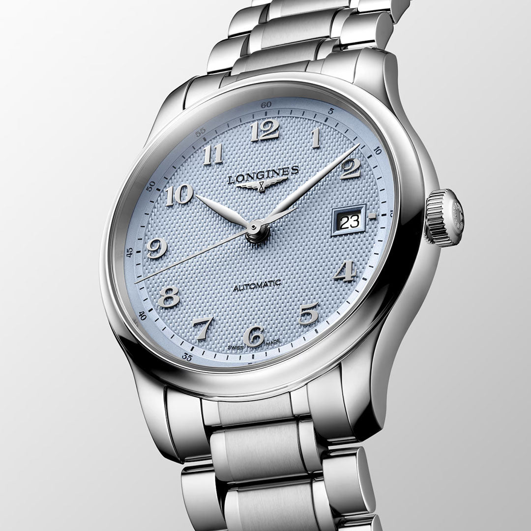 A close-up of the Longines Master Collection Automatic 39mm Watch by Longines, featuring a textured light blue dial, silver hour markers, date window at 3 o’clock, and a sleek metal bracelet against a light gray background—a luxury timepiece crafted for timeless elegance.
