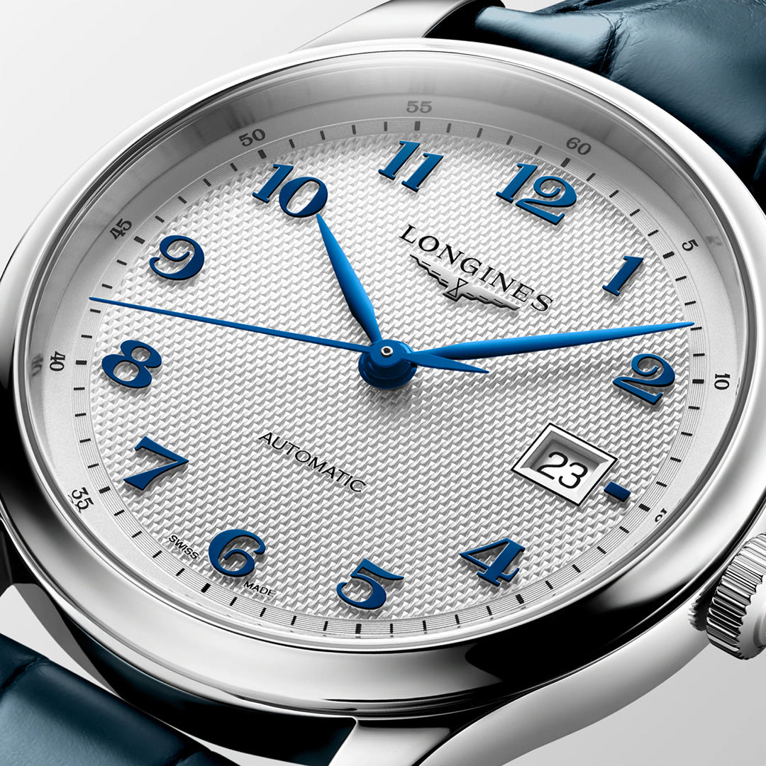 The Longines Master Collection Automatic 41mm Watch by Longines features a silver case, blue numerals and hands, a textured white dial with a date window at 3 o’clock, and a blue leather strap. Displayed in close-up with prominent branding and “AUTOMATIC” text, this refined Swiss timepiece exemplifies the luxury craftsmanship for which the Longines Master Collection is renowned.