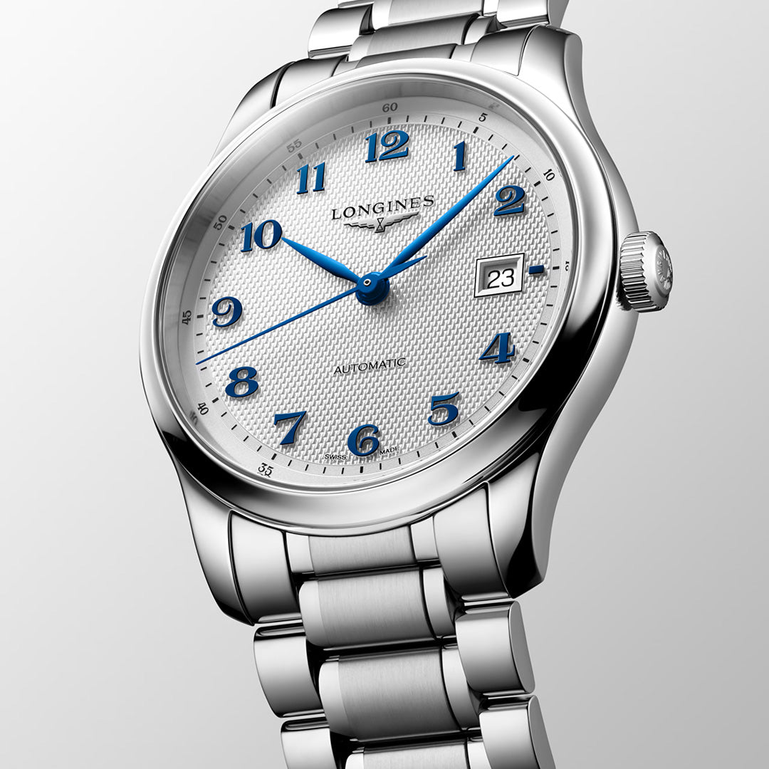 The Longines Master Collection Automatic 41mm Watch features a stainless steel bracelet, a silver-toned textured white dial with striking blue hands and numerals, diamond indexes, and a date window at the 3 o’clock position. Shown at an angle on a light gray background, this timepiece from Longines embodies the elegance and tradition of classic watchmaking.