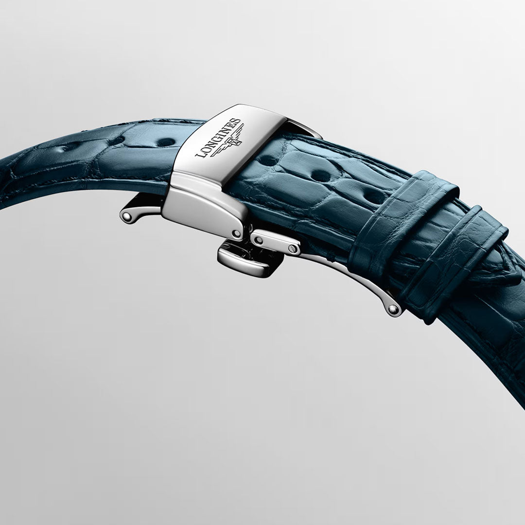 Close-up of a blue, crocodile-patterned watch strap with a stainless steel clasp engraved with the Longines logo, set against a plain, light background—an elegant detail that highlights the craftsmanship of luxury timepieces such as the Longines Master Collection Automatic 41mm Watch by Longines.