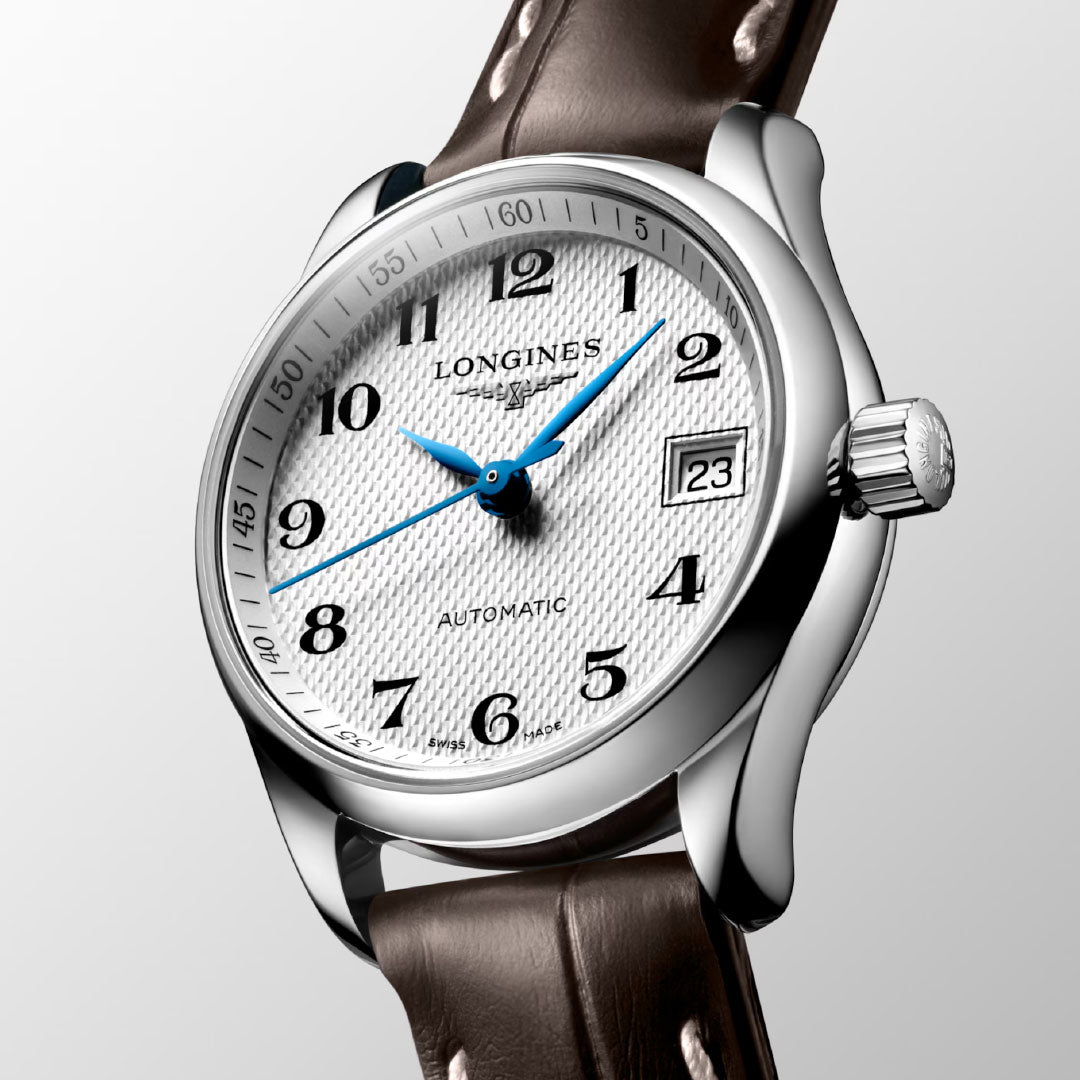 The Longines Master Collection Automatic 25.5mm Watch features a textured white dial with blue hands, black numerals, a date window at “23,” and comes with a brown leather strap—showcasing Longines’ timeless luxury craftsmanship.