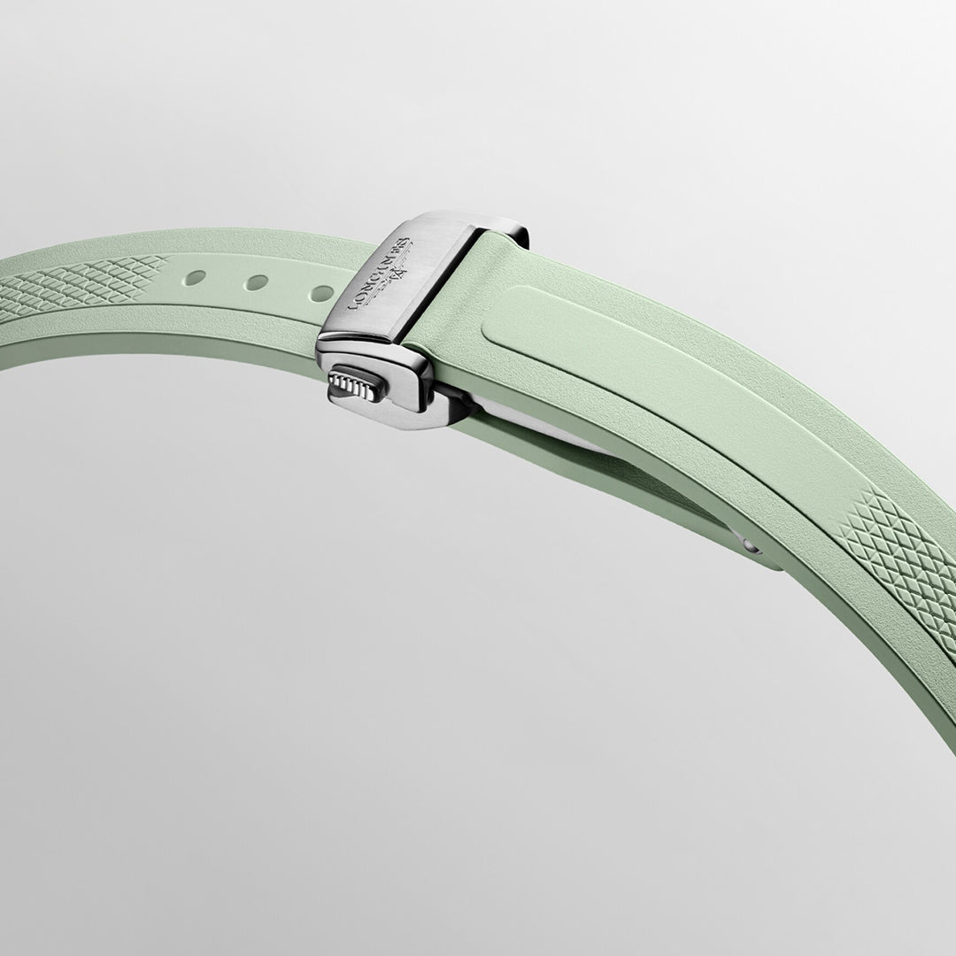 The image features a detailed view of the light green strap from the Longines Conquest Automatic 34mm Watch, complemented by a silver clasp. The strap presents a delicate textured pattern near the clasp with engraved text, epitomizing Longines' commitment to horological excellence through its sleek and contemporary design.