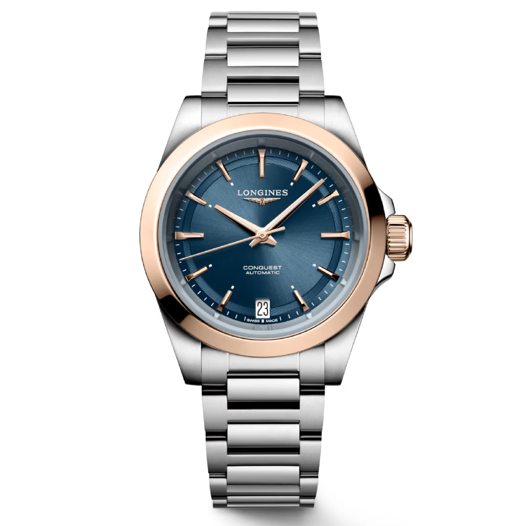 Introducing the Longines Conquest Automatic 34mm Watch, a masterpiece of horological excellence. This luxurious wristwatch features a stainless steel and rose gold band, complemented by a striking blue dial adorned with rose gold hour markers. Its elegant face prominently showcases the Longines brand and "Conquest Automatic," along with a date display at the 6 o'clock position.