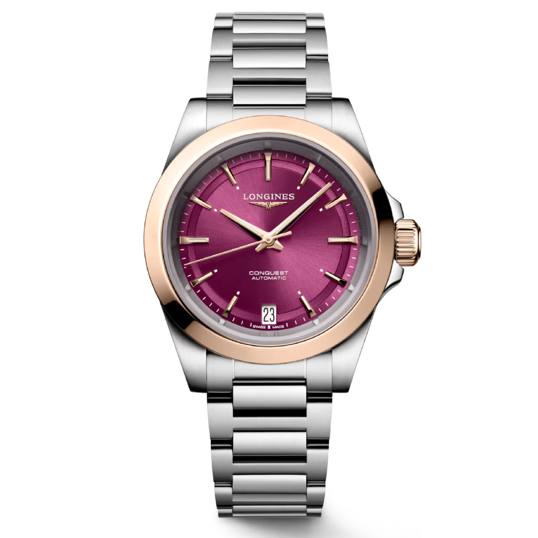 The Longines Conquest Automatic 34mm Watch showcases a silver metal band paired with a rose gold bezel and a sophisticated purple dial. It features elegant gold hands, a date window at the 6 o'clock position, and proudly displays the "Longines" logo on its face, capturing the essence of horological excellence.