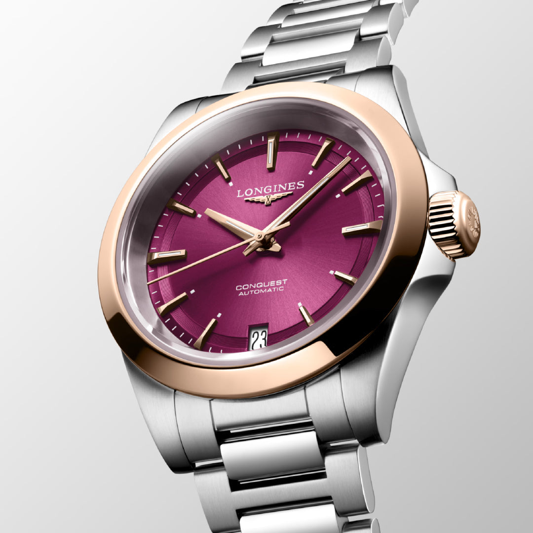 The Longines Conquest Automatic 34mm Watch exemplifies horological excellence with its metallic strap and gold bezel. Its magenta dial is beautifully accented by gold hour markers and hands, while the date is elegantly presented at the 6 o'clock position—truly embodying timeless sophistication.