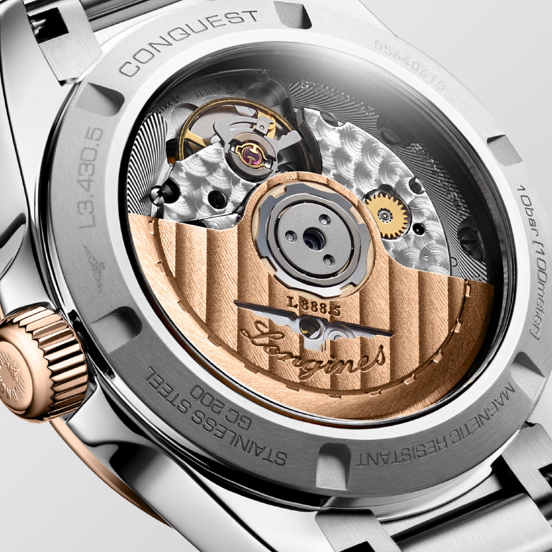 Close-up of a Longines Conquest Automatic 34mm Watch's back, highlighting its horological excellence through intricate mechanical movement. The watch features a transparent case back revealing the gold-toned rotor, gears, and inscriptions, all encased in stainless steel with brand details visible.