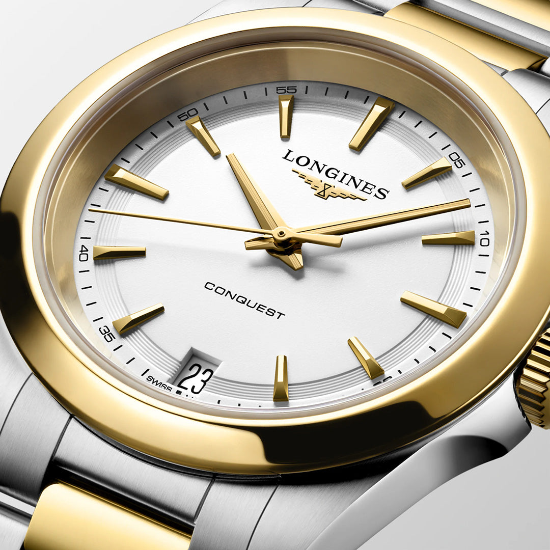 Close-up of a Longines Conquest Quartz 34mm Watch with a white dial, gold-tone hour markers and hands, a date window at the six o’clock position, and a two-tone silver and gold stainless steel link bracelet.