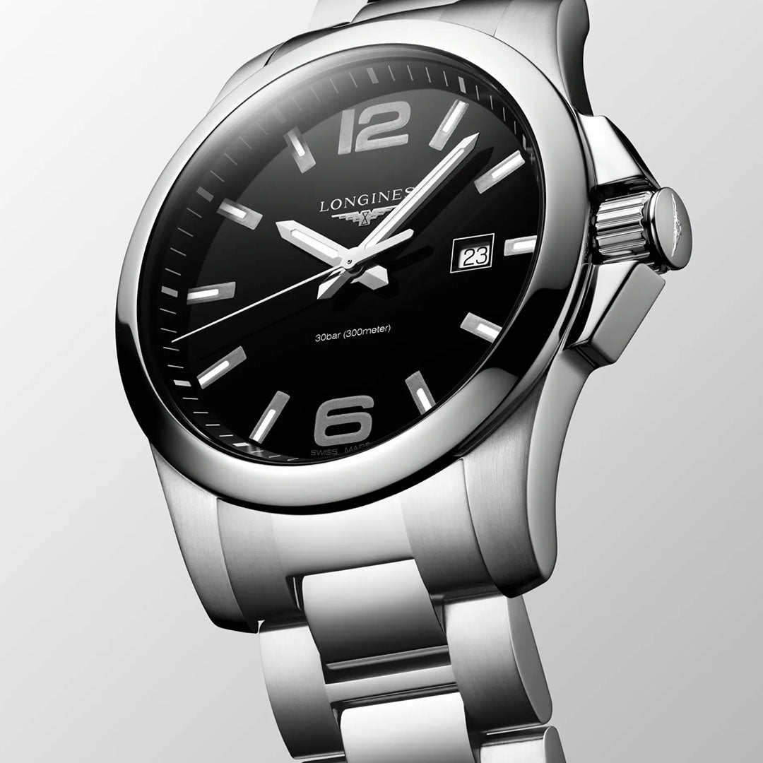 A close-up of the Longines Conquest Quartz 43mm Watch highlights its sporty elegance with a black dial, silver markers, bold 12 and 6 numerals, and date at 3 o’clock—an ideal everyday timepiece from Longines.