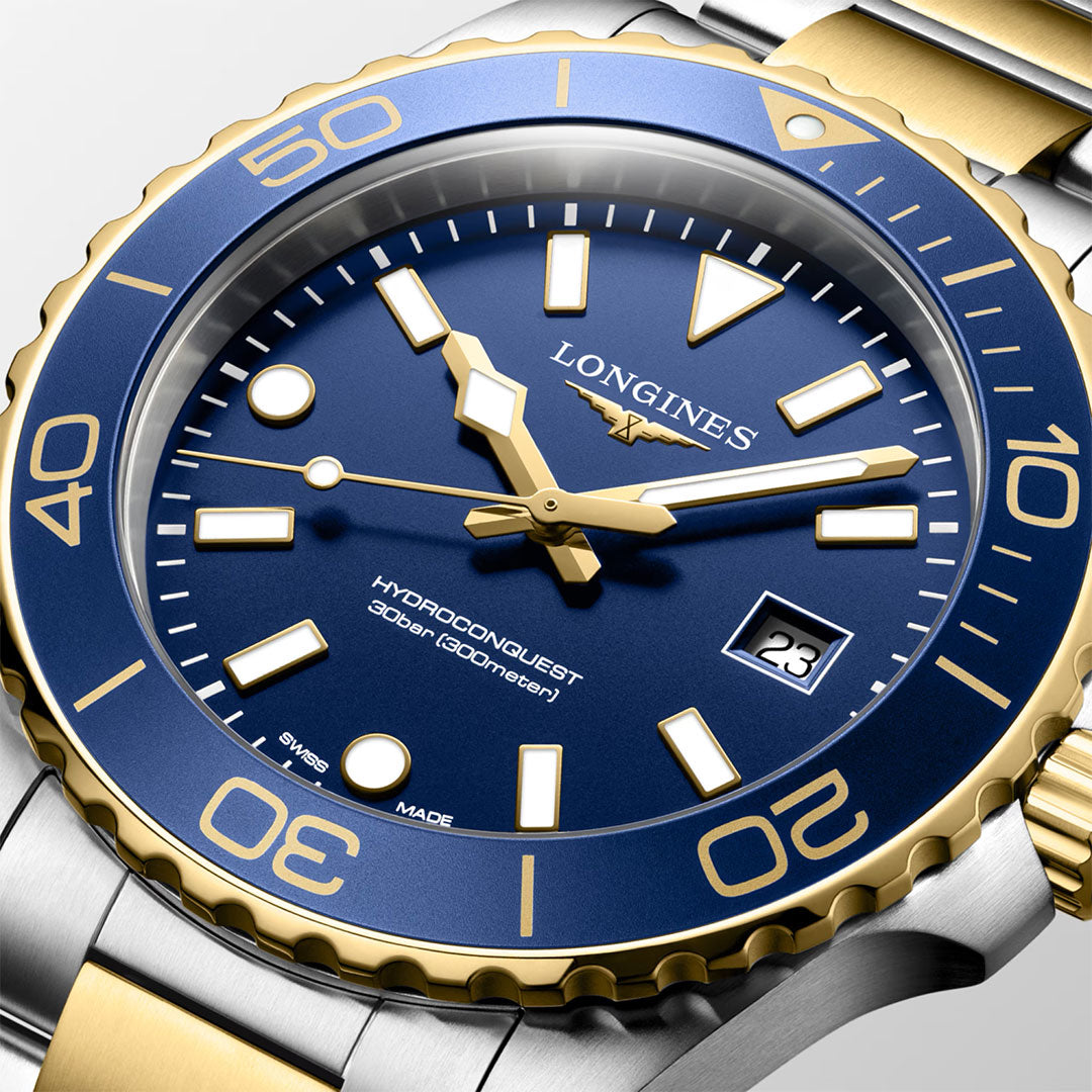 Close-up of the Longines HydroConquest Quartz 42mm Watch by Longines—a highlight in Swiss watchmaking and the sport watch category. This model showcases a striking blue and gold bezel, a blue dial with gold accents, and a date window at 3 o’clock. It is water-resistant up to 300 meters and comes with a stainless steel and gold bracelet.