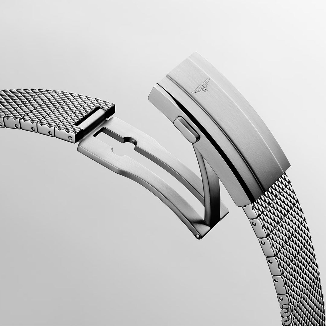 A close-up of a silver mesh watch band with a partially open clasp set against a plain light background. The clasp features a finely engraved winged logo, showcasing the meticulous craftsmanship of the Longines HydroConquest Automatic 39mm Watch and its esteemed place within the Longines collection.