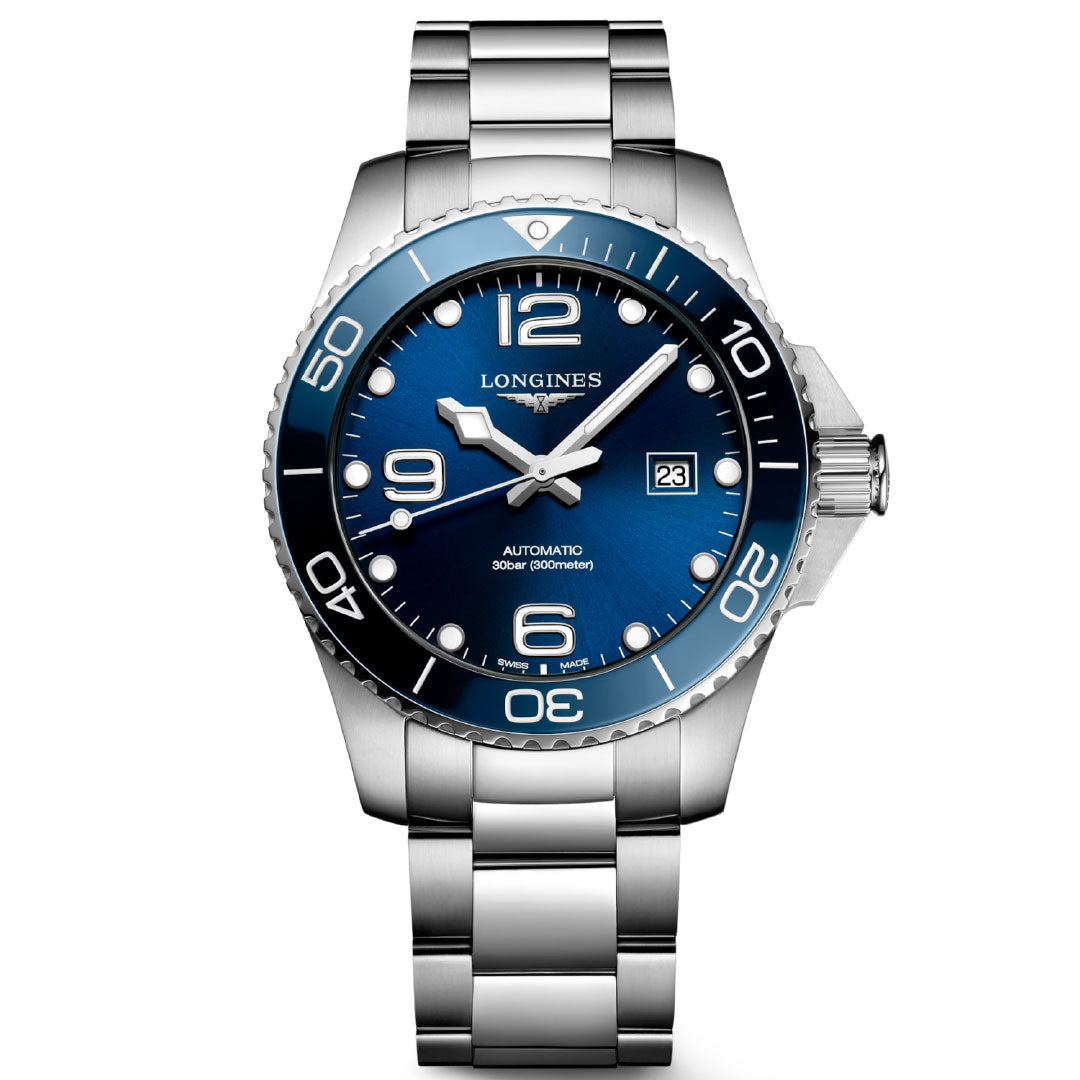 The Longines Hydroconquest Automatic 43mm Watch features a stainless steel case, blue dial, unidirectional rotating bezel with white numerals, silver hands with white accents, silver hour markers, date window at 3 o’clock, and metal bracelet.