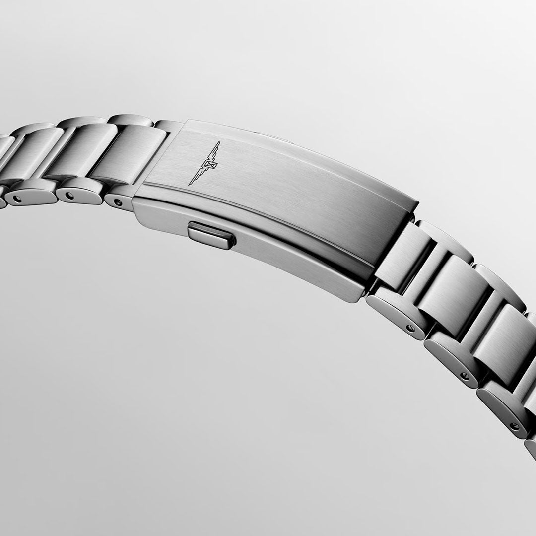 A close-up of the Longines Hydroconquest Automatic 42mm Watch shows its stainless steel bracelet and folding clasp with an engraved wings logo, as the elegant timepiece gleams subtly against a light grey background.