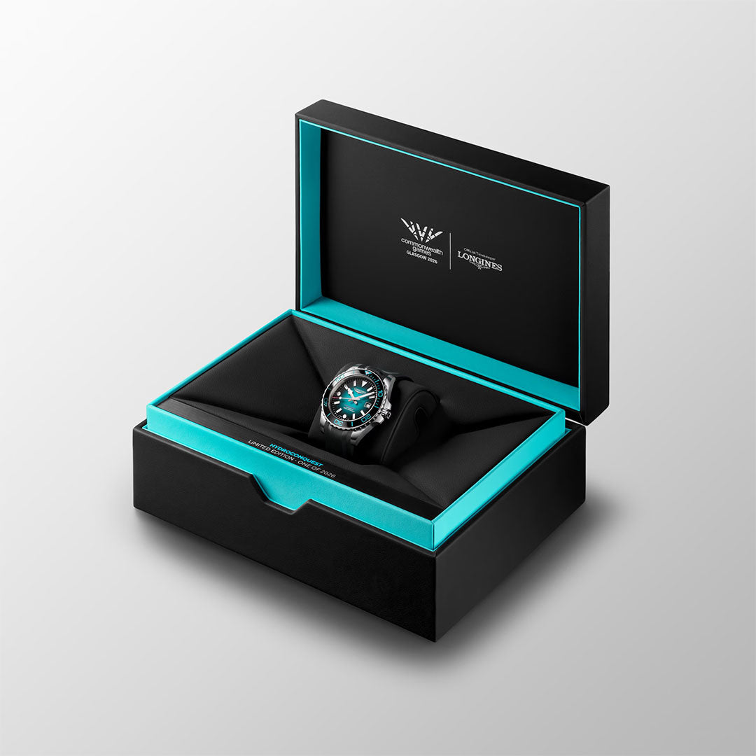 The Longines Hydroconquest 2026 Commonwealth Games Automatic 42mm Watch Limited Edition, featuring a black strap and turquoise accents, is presented in an open black and turquoise Longines box against a light gray background.