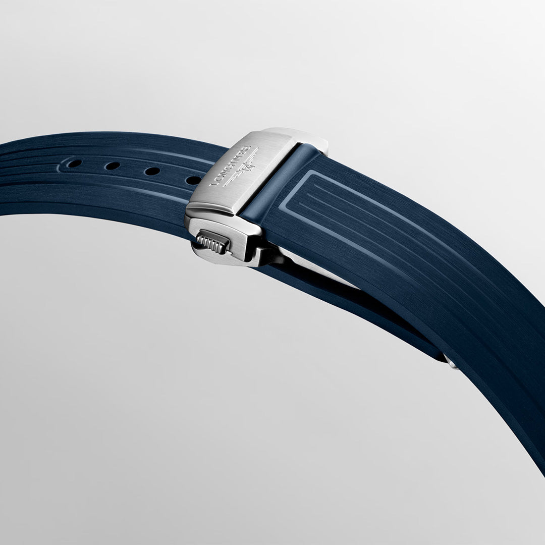 A close-up of a blue rubber watch strap with a silver clasp, set against a plain light background. The clasp, engraved with the Longines logo and belonging to the Longines HydroConquest GMT Automatic 41mm Watch by Longines, displays fine detailing while the strap features subtle linear patterns.