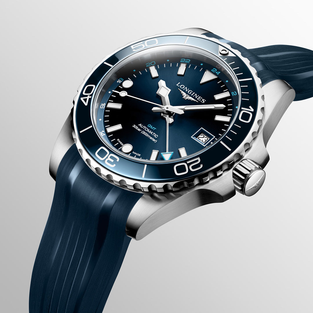 A close-up of the Longines HydroConquest GMT Automatic 41mm Watch by Longines, showcasing a blue dial with Swiss Super-LumiNova white markers and a matching blue rubber strap. The bezel features minute indicators, and the date is displayed at the 3 o’clock position.