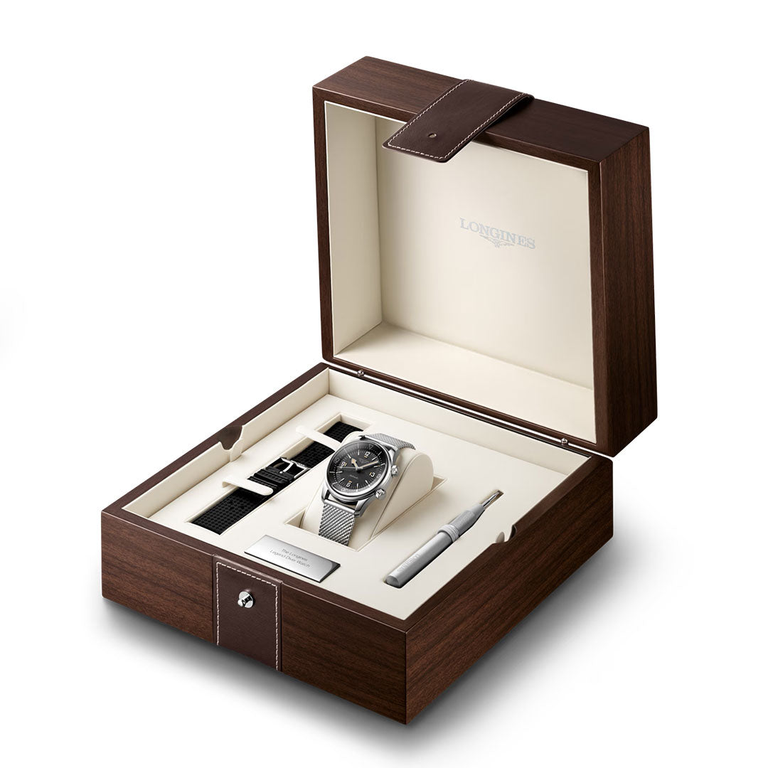The Longines Legend Diver 59 Automatic 42mm Watch set by Longines comes in an open wooden box with a cream interior, featuring a water-resistant watch, interchangeable straps, a stainless steel plaque, and a strap adjusting tool.