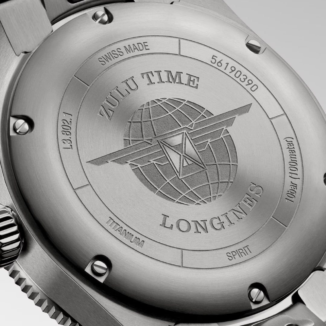 A detailed view of the back of the Longines Spirit Zulu Time Titanium Case and Titanium Automatic 39mm Watch features engravings of the brand's logo, showcasing wings over a globe. The inscriptions read "Zulu Time," "Swiss Made," and "Titanium," accompanied by serial numbers. This chronometer-certified watch comes with a brushed metallic finish and offers dual time zone functionality.