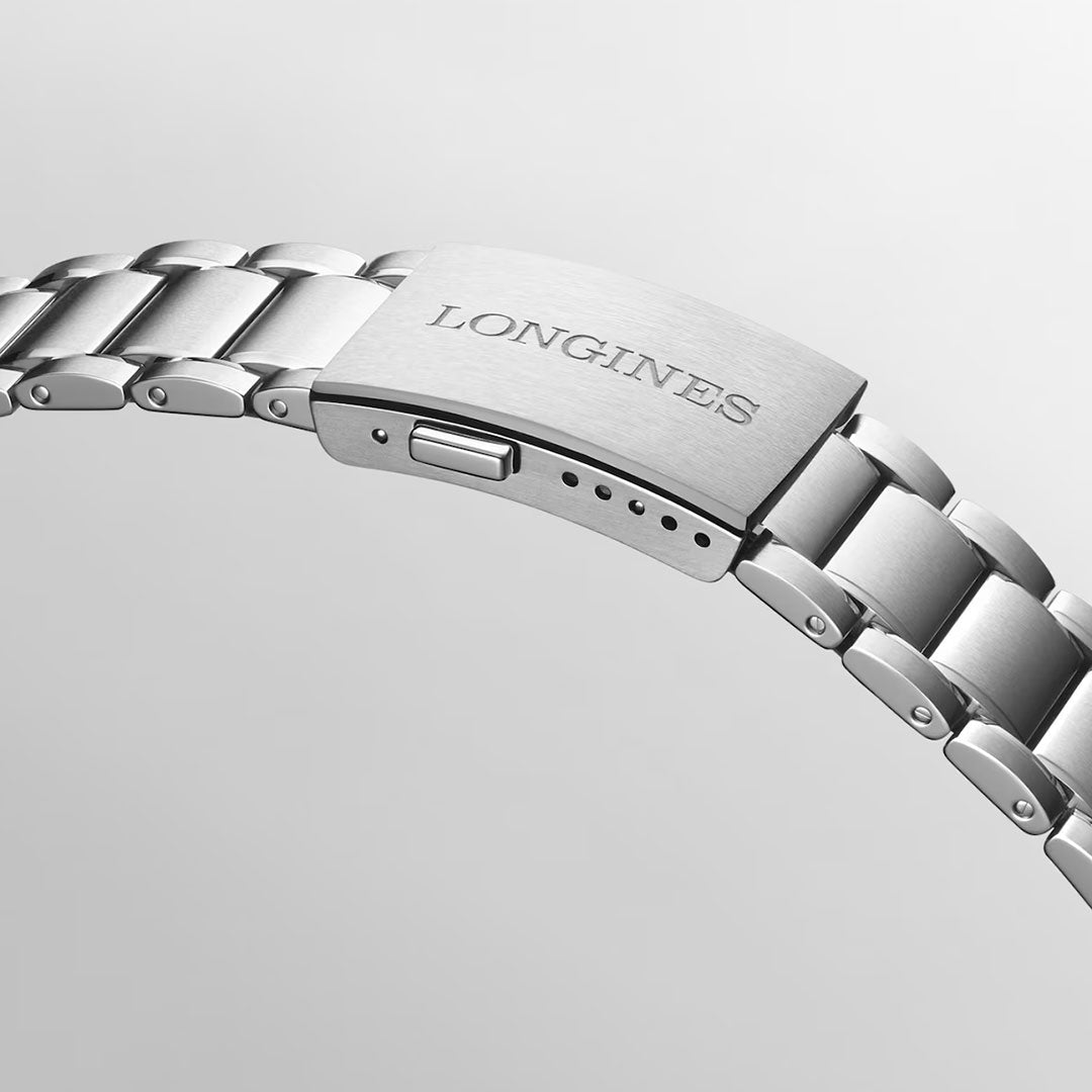 A close-up of a silver metal watch bracelet with a clasp engraved with the brand name “Longines” on a light gray background, showcasing the craftsmanship of chronometer-certified timepieces like the Longines Spirit Zulu Time Automatic 39mm Watch.