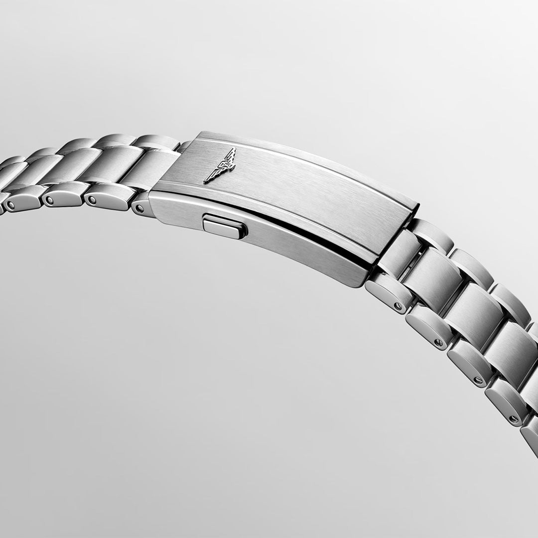 Close-up of a silver metal bracelet with a brushed clasp, featuring a small engraved winged logo, set against a light gray background—a refined detail that reflects the distinguished Longines Spirit Pilot Automatic 39mm Watch and its chronometer-certified heritage.