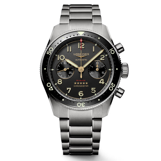 The Longines Spirit Flyback Titanium Automatic 42mm Watch blends aviators' spirit with elegance, featuring a stainless steel bracelet, a black dial with gold numerals, three subdials, and a red-tipped hand at 12 o'clock. This chronometer-certified piece has a minimalist black bezel with luminous markers.