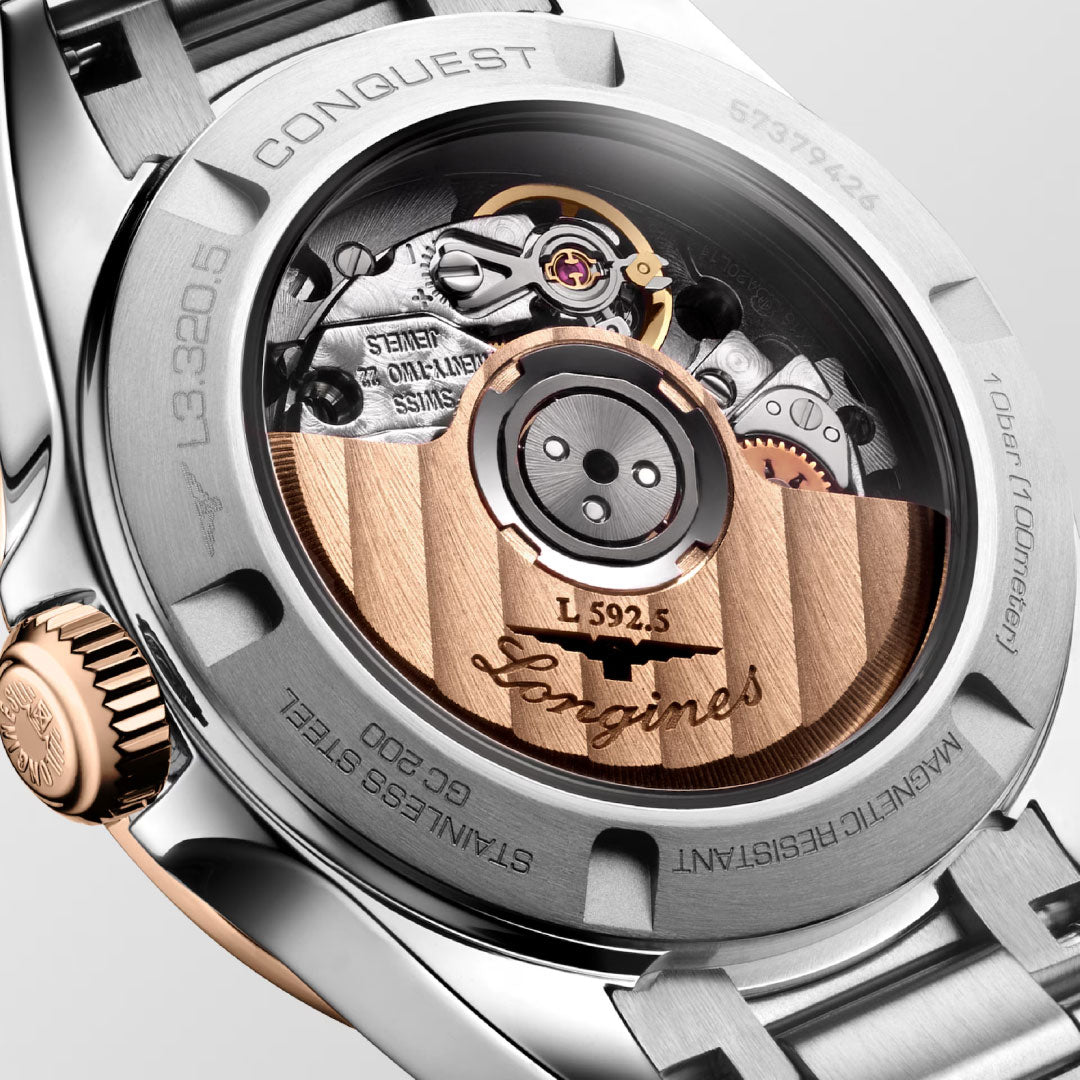 Close-up of the Longines Conquest Automatic 30mm Watch reveals its intricate mechanical movement and engraved details through a transparent stainless steel and rose gold case back—a true showcase of sporty elegance from Longines.
