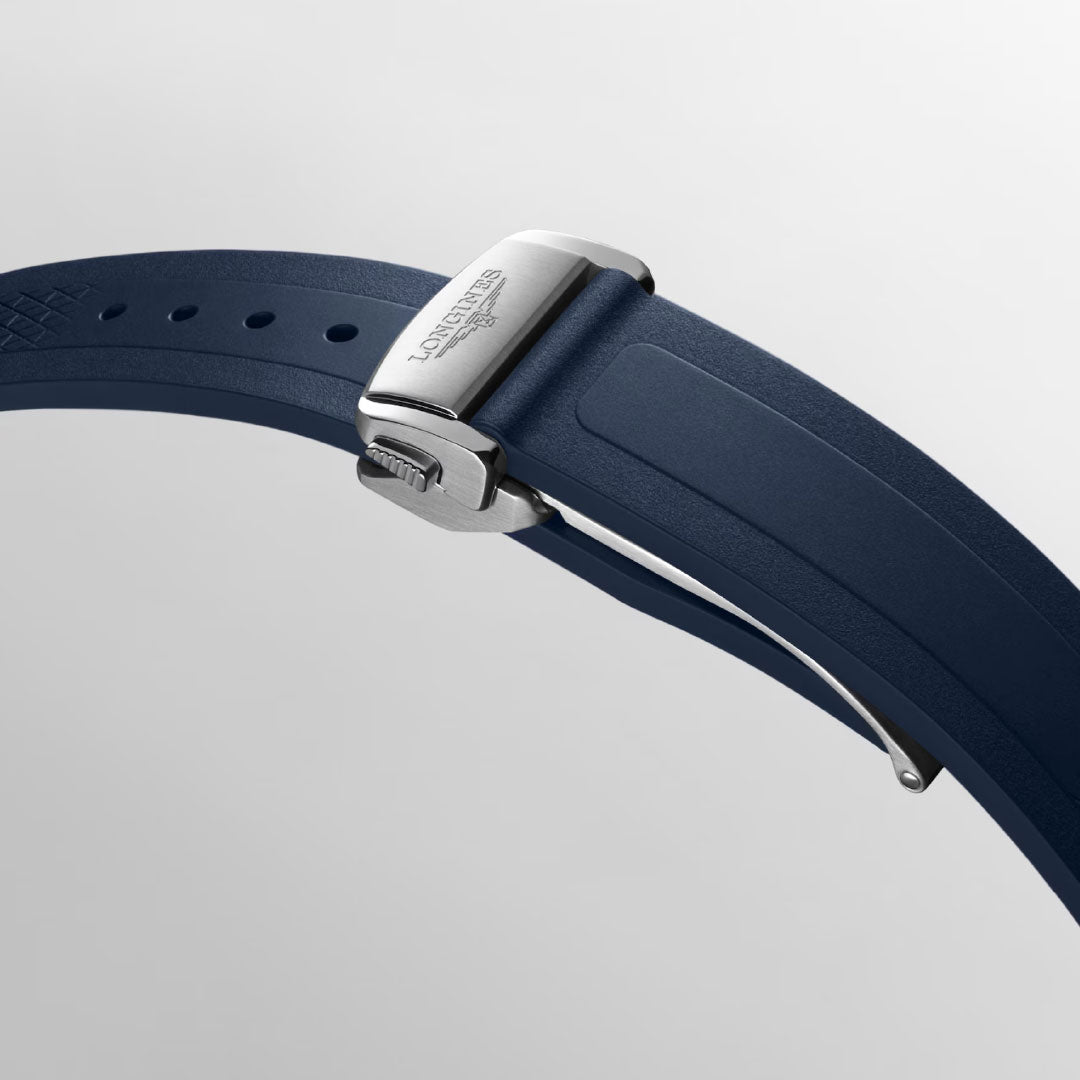 Close-up of a blue rubber strap with a silver deployment clasp bearing the Longines logo, shown on a light gray background—an elegant detail from the Longines Conquest Automatic 38mm Watch.