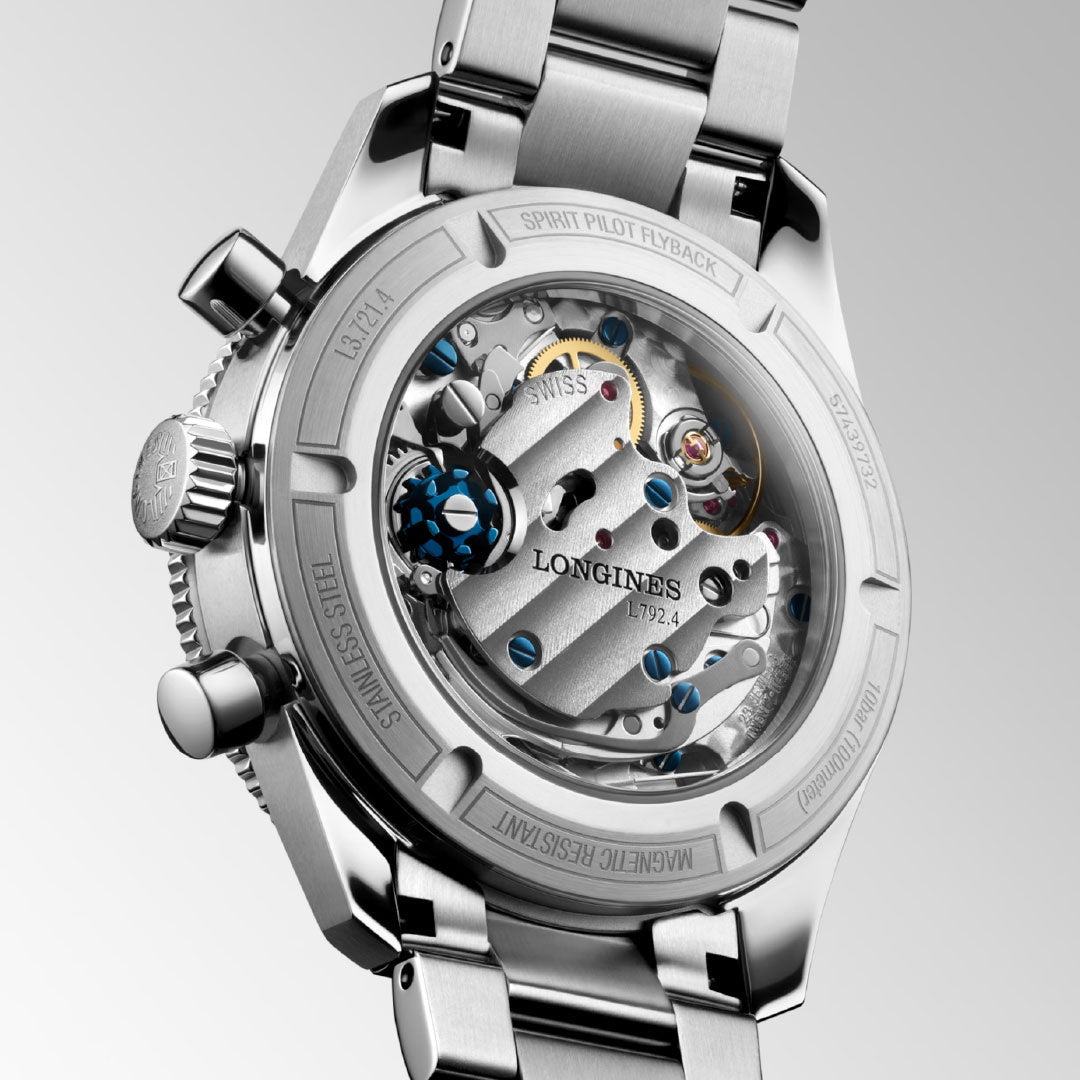 A close-up of the Longines Spirit Pilot Flyback Automatic Manual Winding 39.5mm Watch showcases its mechanical movement and detailed gears through a transparent case back, with “Longines” and “Stainless Steel” finely engraved.