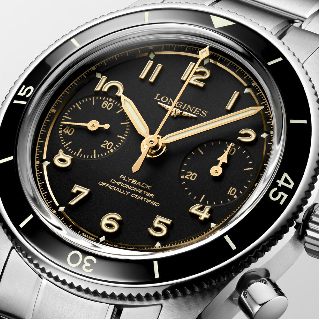 Close-up of the Longines Spirit Pilot Flyback Automatic Manual Winding 39.5mm Watch, featuring a black dial with gold Arabic numerals, two subdials, stainless steel bezel and bracelet, gold hands and markers, and flyback chronograph.