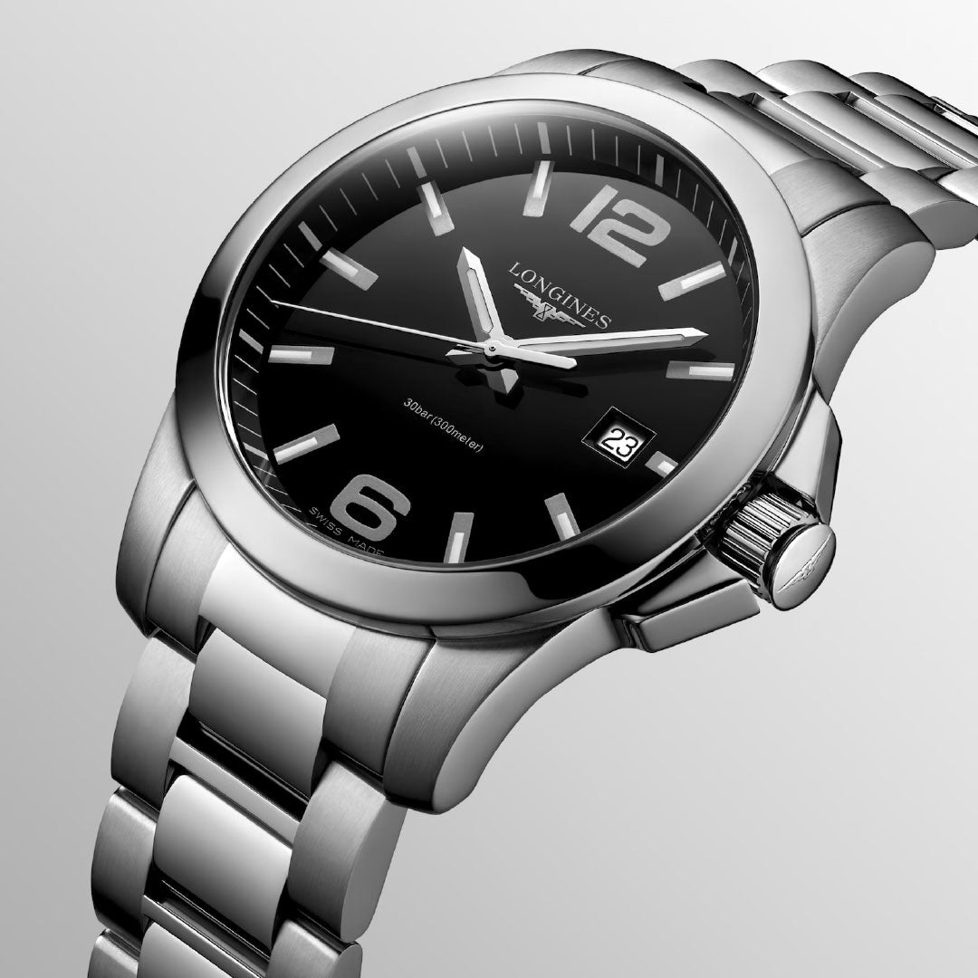 A close-up of the Longines Conquest Quartz 41mm Watch featuring a black dial, silver hour markers, and date window at 3 o’clock, displayed against a light gradient backdrop.