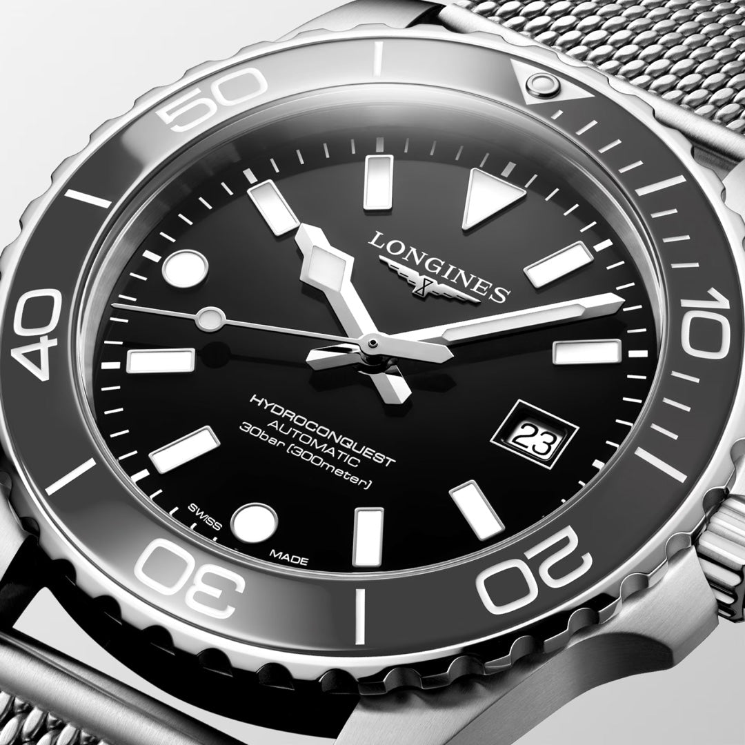 A close-up of the Longines Hydroconquest Automatic 42mm Watch, showcasing its black dial with bold white markers, date at 3 o’clock, stainless steel mesh strap, and automatic movement, water-resistant to 300 meters.