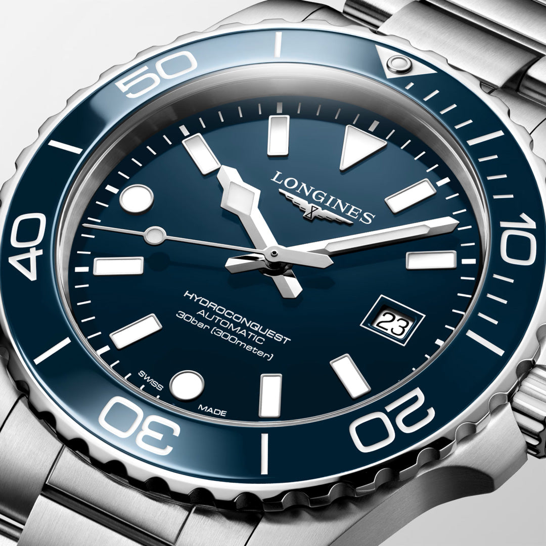 A close-up of the Longines Hydroconquest Automatic 42mm Watch featuring a blue dial, white markers, date at 3 o’clock, and stainless steel bezel and bracelet. This Longines timepiece is water-resistant to 300m.