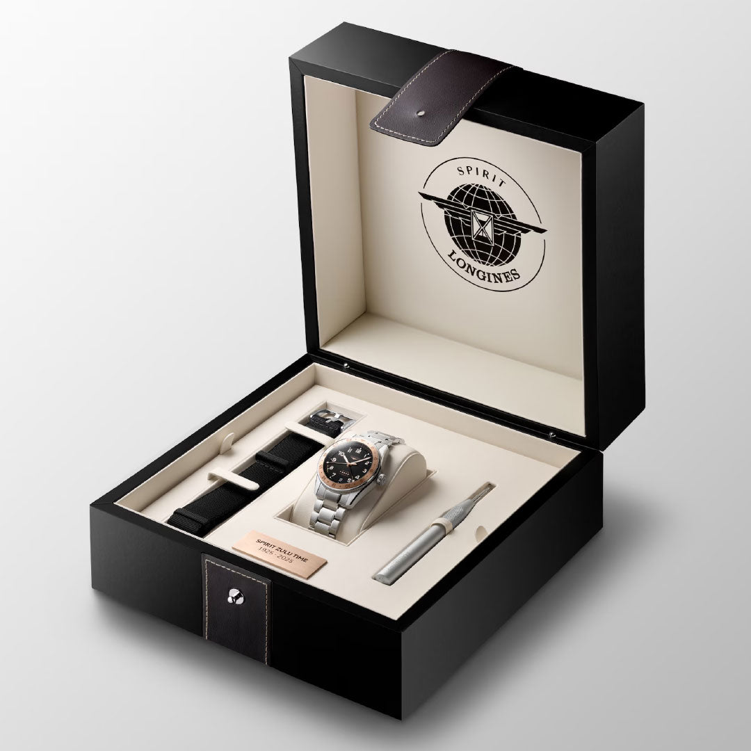 The Longines Spirit Zulu Time 1925 Automatic 39mm Watch comes in an open black box with a silver dual time zone watch, extra black strap, tool, metal plate, and Longines logo on the inside lid.