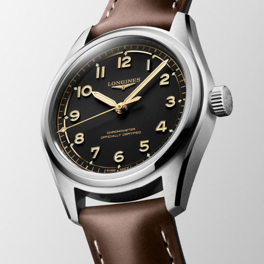 The Longines Spirit Pilot Automatic 39mm Watch features a black dial with gold numerals and hands, a stainless steel case, and a brown leather strap, shown angled on a light background.