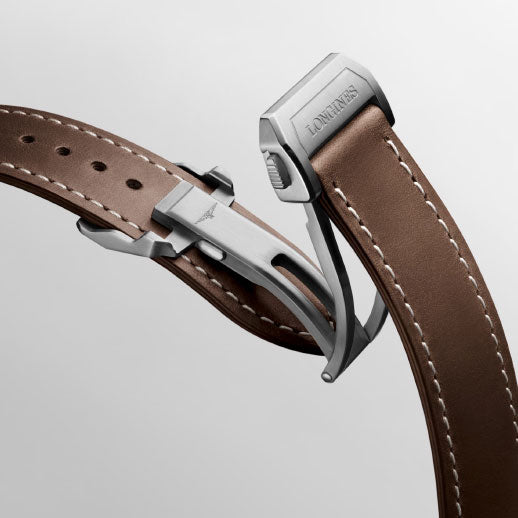 Close-up of the Longines Spirit Pilot Automatic 39mm Watch’s brown leather strap with white stitching and a stainless steel deployment clasp engraved with the Longines logo, set against a light gray background.