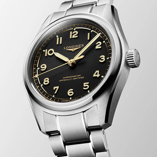 The Longines Spirit Pilot Automatic 39mm stainless steel watch, featuring a black dial with gold-tone numerals and hands on a metal bracelet, is displayed at an angle on a light gray background.