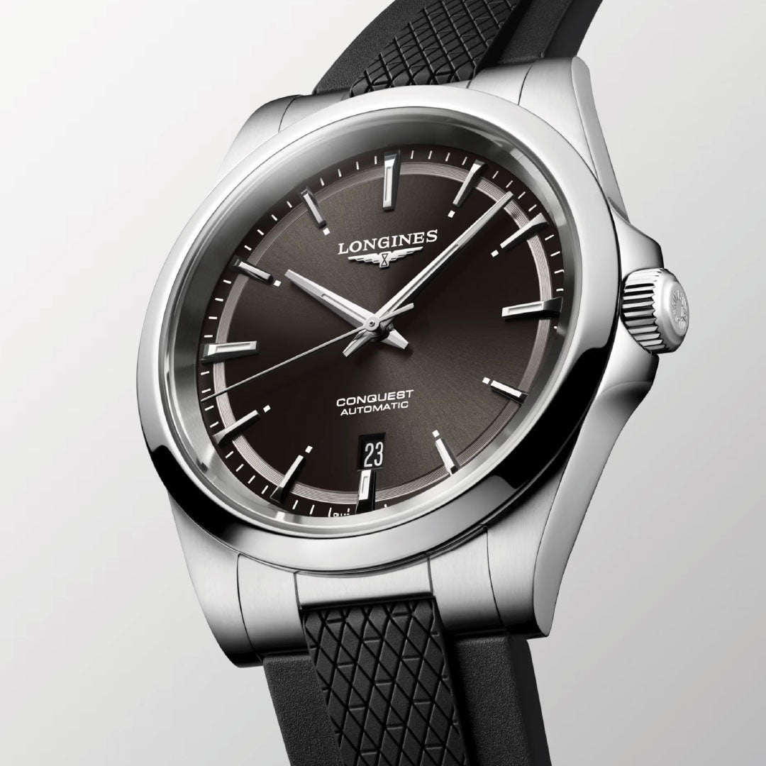 A close-up of the Longines Conquest Automatic 41mm Watch featuring a black dial, silver hour markers, date at 6 o'clock, and a textured black strap—an ideal everyday choice from Longines against a light backdrop.