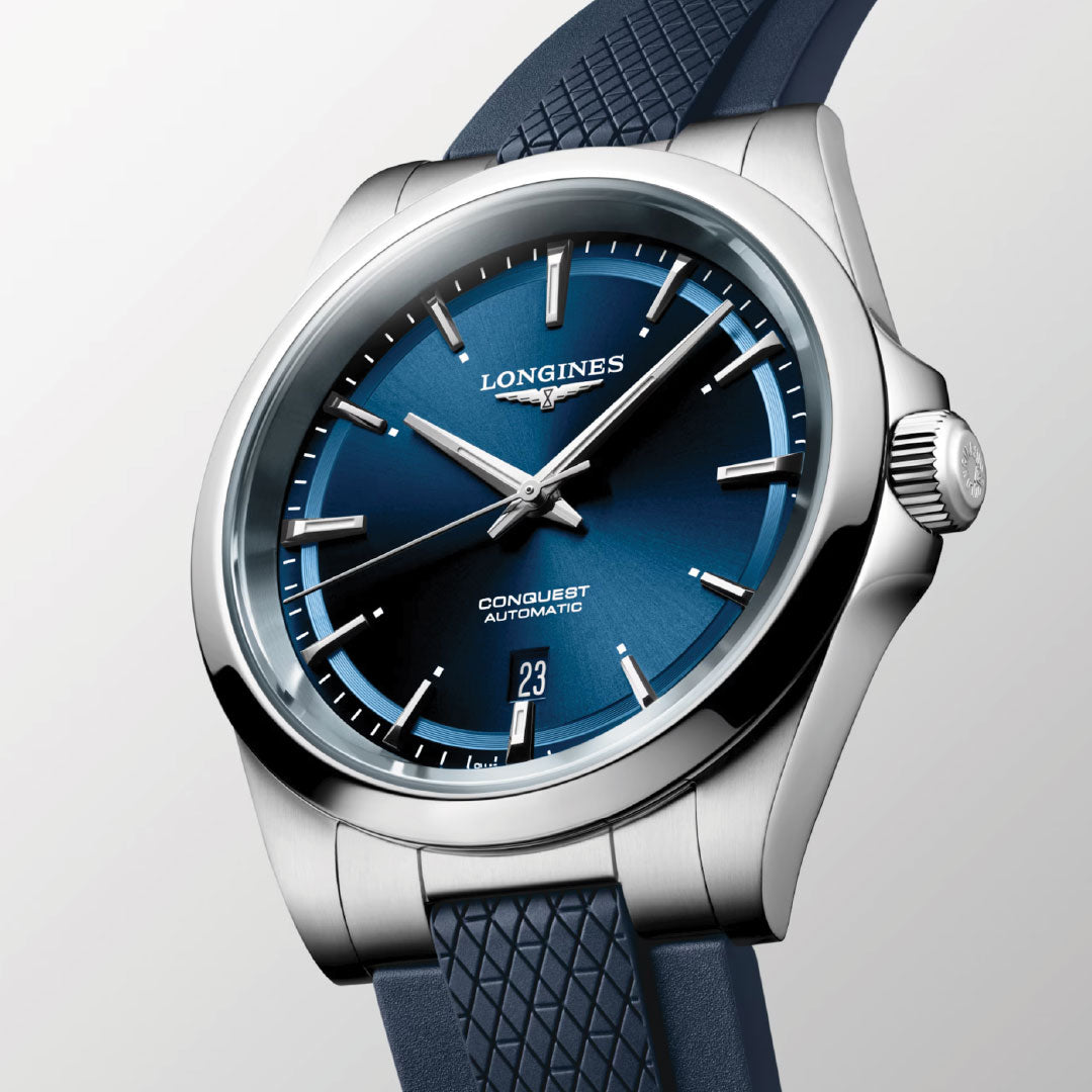 The Longines Conquest Automatic 41mm Watch features sporty elegance with a blue dial, silver markers and hands, date at 6 o'clock, textured blue strap, and polished stainless steel case.