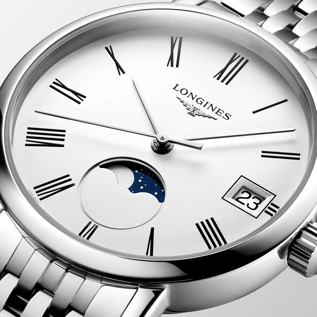 A close-up of the Longines Elegant Collection Moonphase Quartz 30mm Watch highlights its minimalist elegance, featuring a white face with Roman numerals, a moon phase indicator, and a date display set to the 23rd. The polished metal bracelet complements Longines' renowned watchmaking tradition.