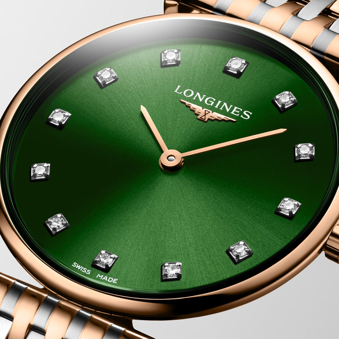 Close-up of the Longines La Grande Classique Quartz 29mm Watch, featuring a green dial, gold hands, diamond hour markers, and a two-tone metal band. The Longines logo and "SWISS MADE" text highlight its classic elegance.