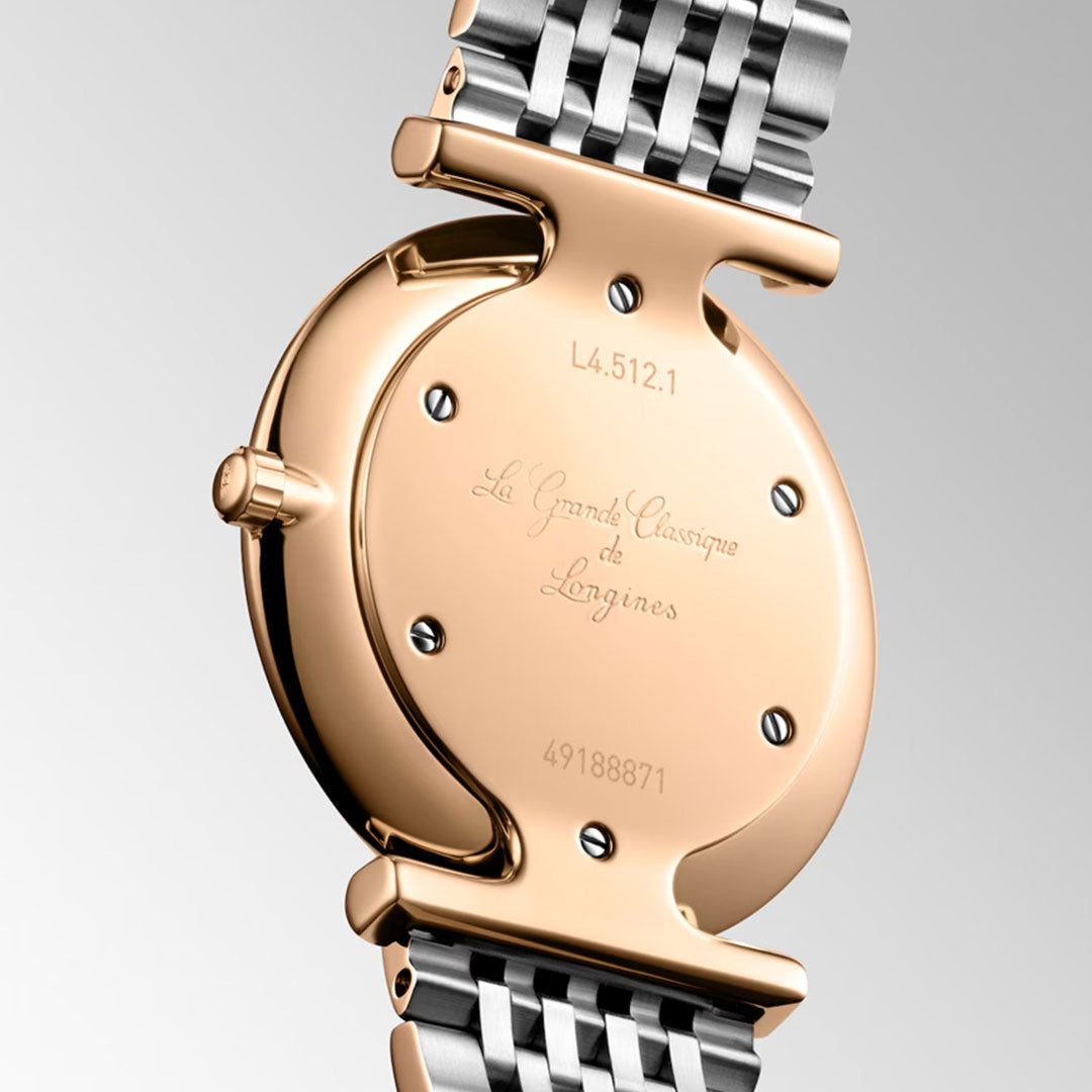 Close-up of the back of the Longines La Grande Classique Quartz 29mm Watch, featuring a gold case and silver-gold metal band engraved with “La Grande Classique de Longines,” displaying its refined elegance and brand craftsmanship.