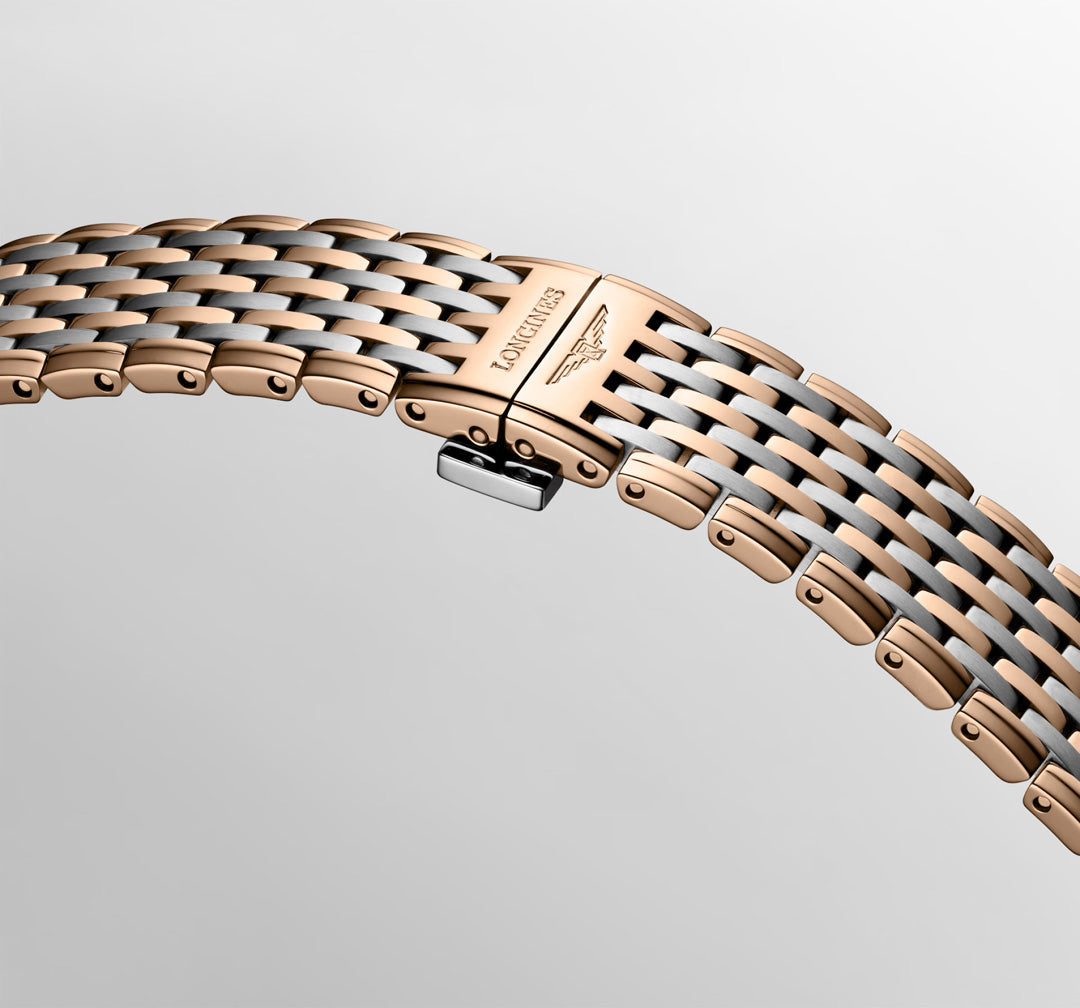 A close-up of the Longines La Grande Classique Quartz 29mm Watch shows its two-tone rose gold and silver bracelet with “LONGINES” and the winged hourglass logo engraved on the clasp, embodying classic elegance against a light background.