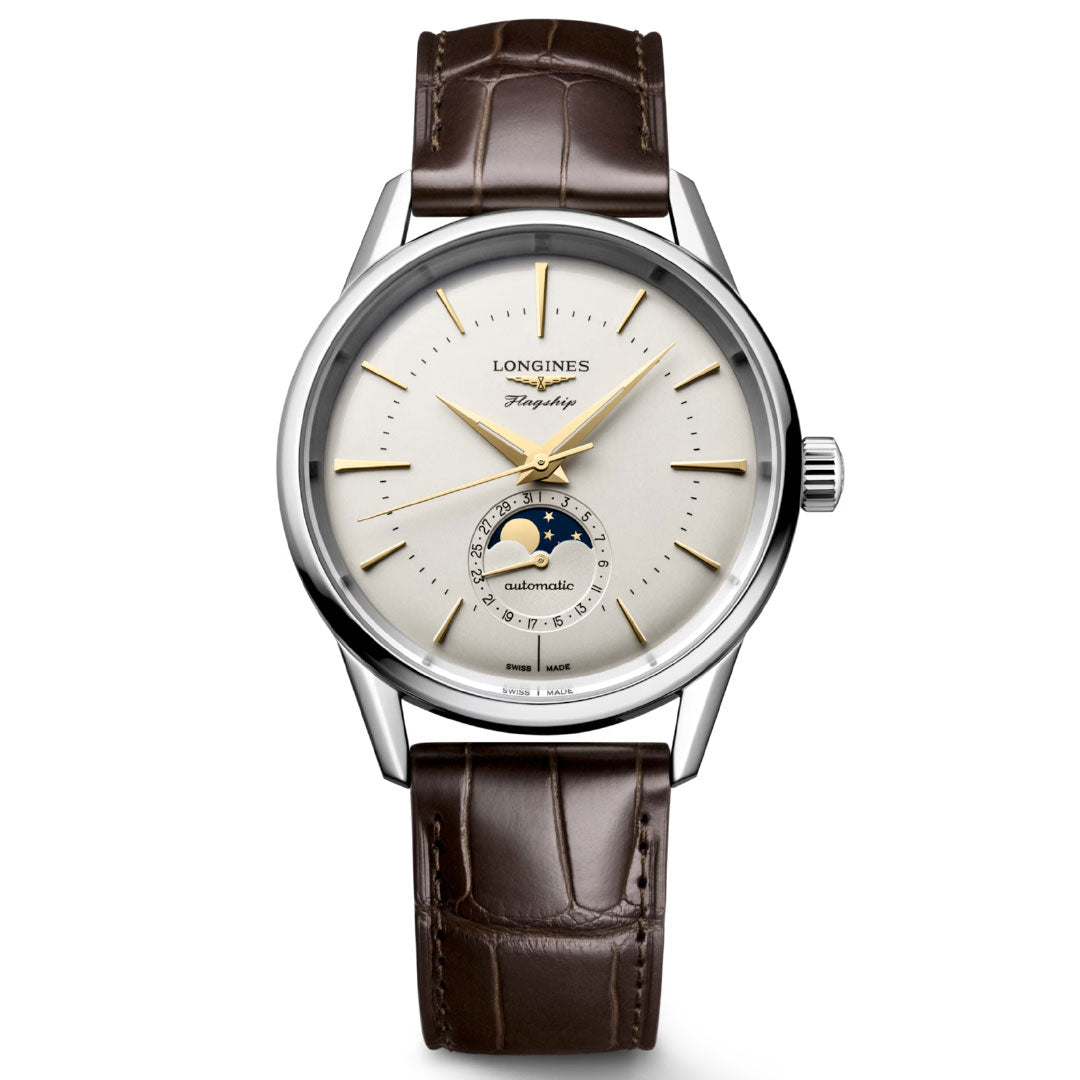 The Longines Flagship Heritage Moonphase Automatic 38.5mm Watch features a brown leather strap, silver case, white dial, gold hour markers, and a moon phase display—an ideal choice for fans of classic Swiss watchmaking.