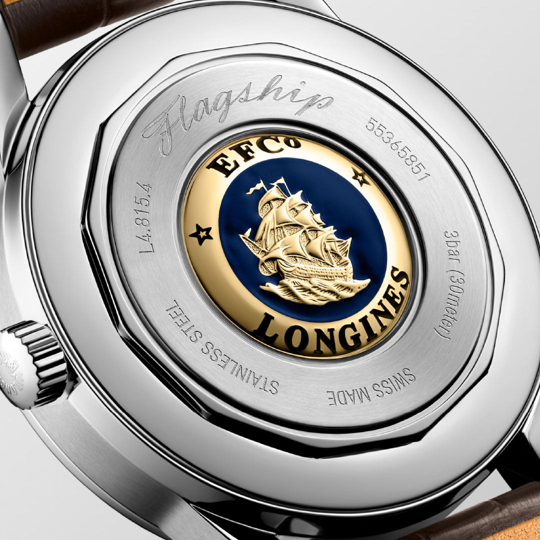 Close-up of the Longines Flagship Heritage Moonphase Automatic 38.5mm case back, featuring a gold and blue enamel caravel medallion, engraved with "Flagship," numbers, "SWISS MADE," and "STAINLESS STEEL" for classic appeal.