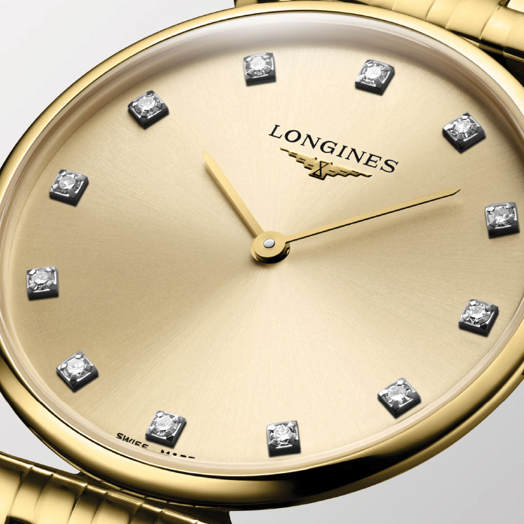 Close-up of the Longines La Grande Classique De Longines Quartz 39mm Watch, featuring a champagne dial with diamond hour markers, gold hands, and bracelet. The elegant minimalist design displays the Longines logo.