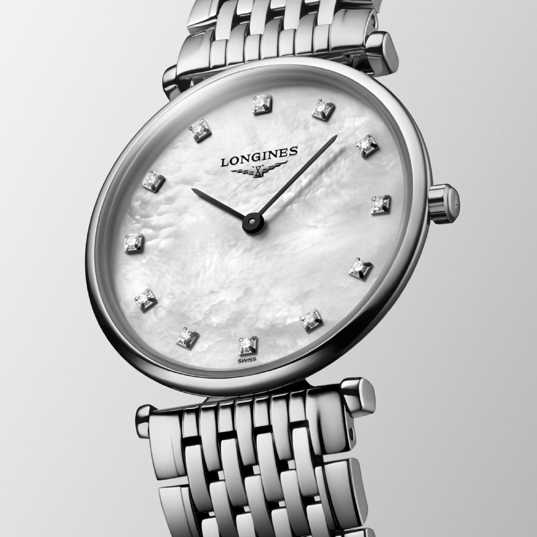 A close-up of the Longines La Grande Classique Quartz 29mm Watch showcases its silver tone, mother-of-pearl dial with diamond hour markers, and metal link bracelet against a light gray background—a classic elegant timepiece.