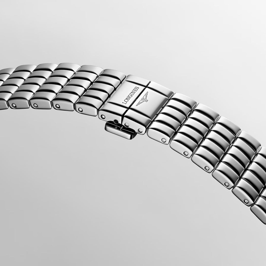 Close-up of a silver-toned Longines Mini Dolcevita Quartz 21.5 x 29mm Watch stainless steel bracelet with a deployment clasp featuring the engraved brand name and logo.