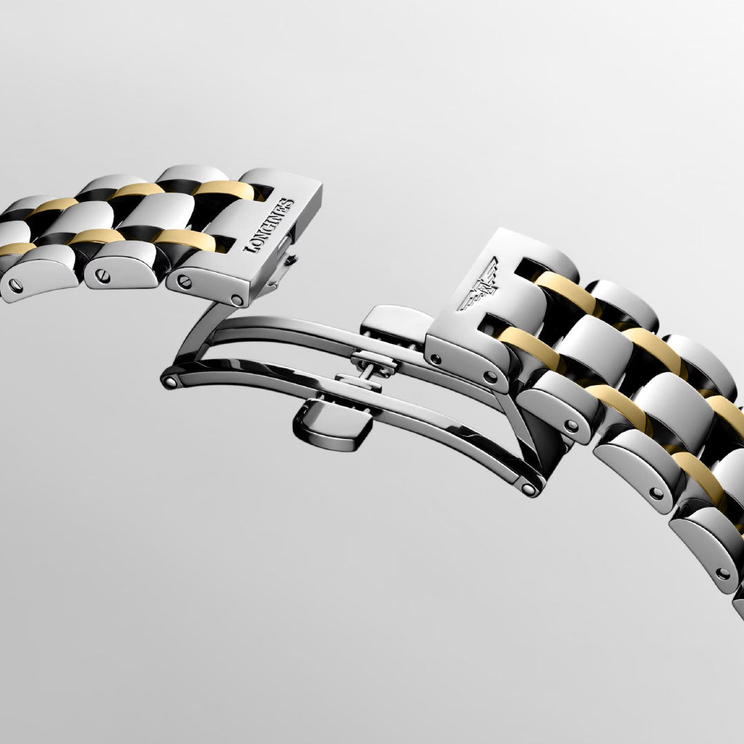 Close-up of a two-tone bracelet on the Longines Dolcevita Quartz 20.8 x 32mm Watch, featuring a partially open butterfly clasp engraved with the Longines name and logo, set against a light grey background.