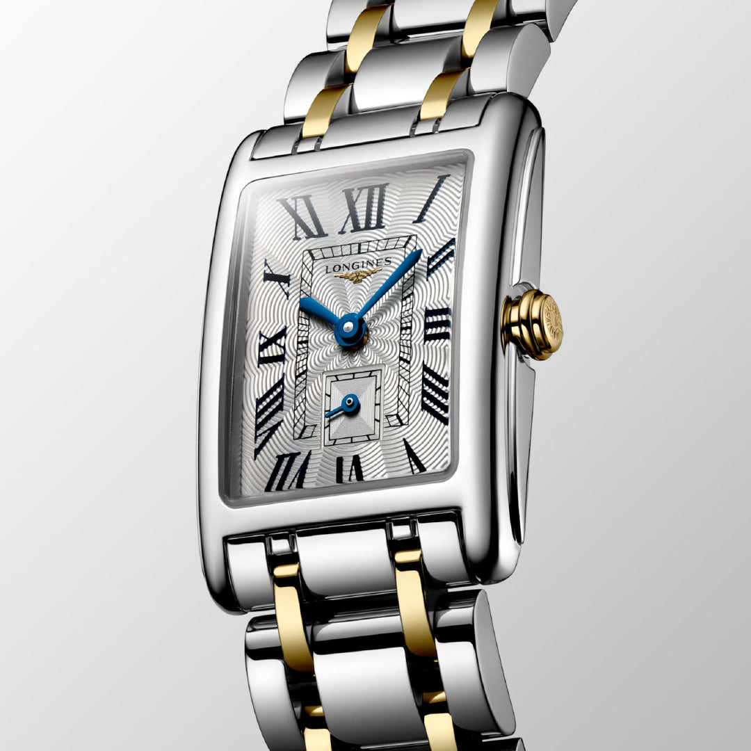 The Longines Dolcevita Quartz 20.8 x 32mm Watch features a rectangular silver dial with blue hands, Roman numerals, a small seconds subdial, and a two-tone gold and silver metal bracelet—iconic elegance on a light gray background.