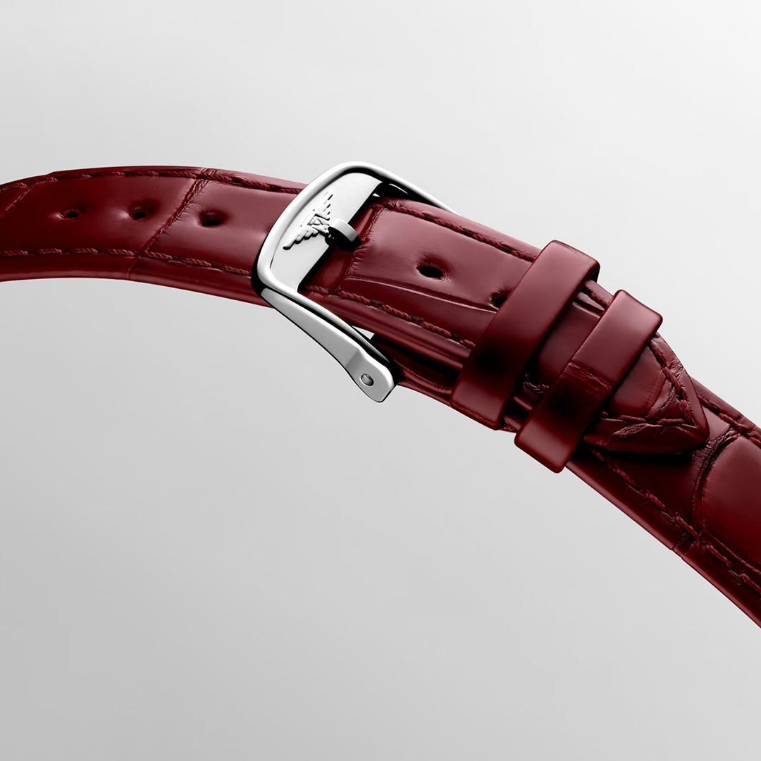 A close-up of a red leather strap with a silver buckle, showcasing visible stitching and an engraved Longines logo on the buckle, set against a light gray background—an exquisite detail that embodies the classic sophistication of the Longines Dolcevita Quartz 23.3 x 37mm Watch.